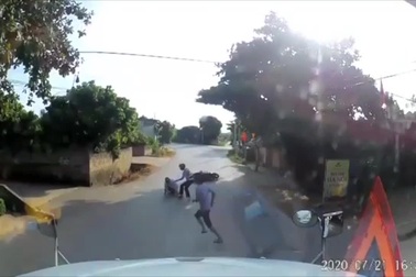 Người đi xe máy ngã nhào trước mũi xe container để tránh trẻ chạy sang đườn