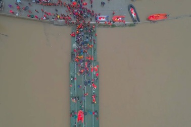 Người dân ở vùng lũ Trung Quốc sơ tán bằng cầu tạm