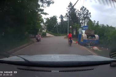 Bé gái đi xe đạp làm rơi em xuống đường mà không hay biết