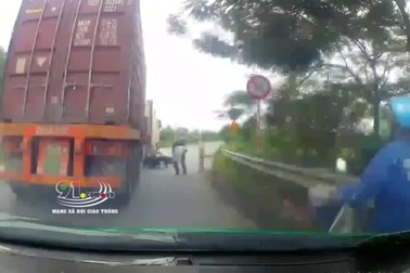 Người đi xe máy thoát chết đầy may mắn dưới gầm xe container