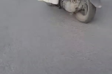 Thanh niên ngồi gác chân, mắt dán vào điện thoại khi chạy xe máy