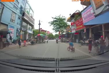 Cậu bé đi xe đạp qua đường mà không thèm quan sát suýt bị ô tô tông