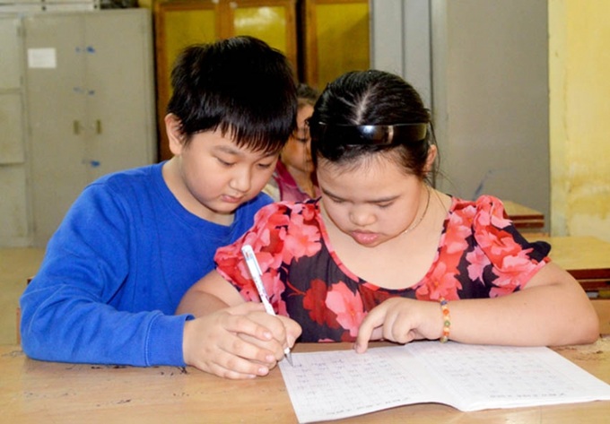 Giúp bạn cùng lớp là học sinh khuyết tật học bài. Ảnh minh hoạ.