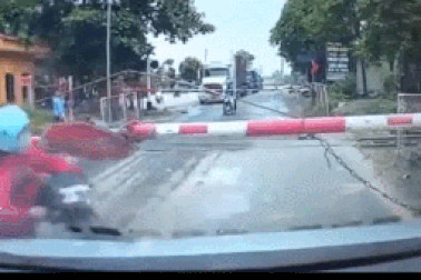 "Nữ ninja" liều lĩnh dắt xe máy chui qua chắn tàu đã đóng để vượt đường sắt