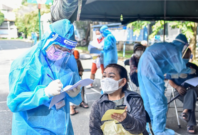 Tình nguyện viên ở TP.HCM đội mưa hướng dẫn người dân đi tiêm vaccine - Ảnh 4.