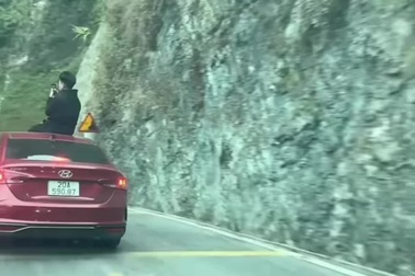 Thanh niên ngồi trên nóc khi ô tô đang chạy trên đường đèo