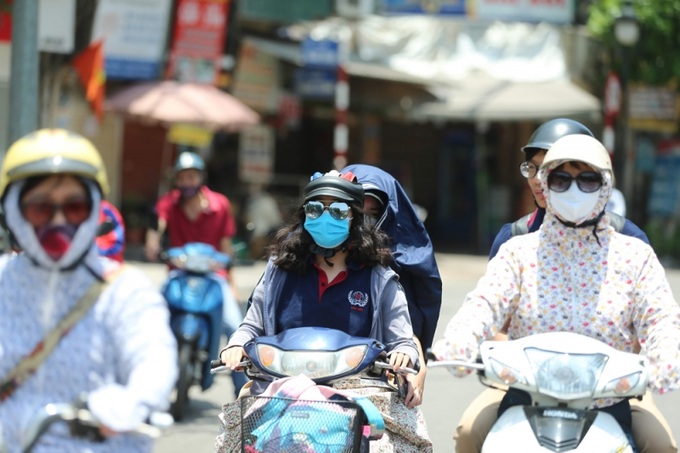 Người dân mặc đồ kín mít tránh nắng, nóng khi di chuyển trên đường.