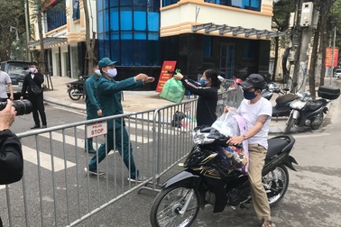 Người dân phố Trúc Bạch nhận nhu yếu phẩm qua hàng rào cách ly