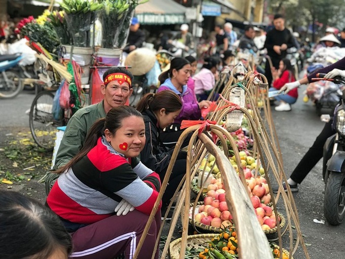 Hàng rong chợ Đồng Xuân vừa bán hàng vừa tranh thủ lên đồ cổ vũ U22 Việt Nam - Ảnh 7.