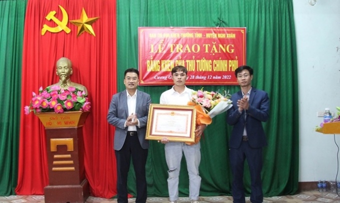Phó Trưởng ban Thi đua - Khen thưởng tỉnh Nguyễn Văn Hoài và Chủ tịch UBND huyện Nghi Xuân Lê Anh Dũng trao bằng khen của Thủ tướng Chính phủ cho Ngô Công Minh.