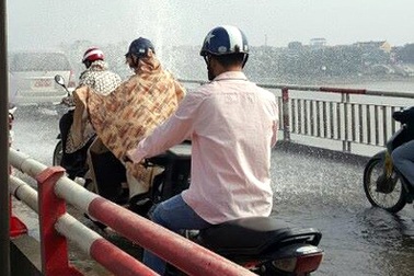 Nước phun xối xả trên cầu Chương Dương, người qua cầu mặc áo mưa giữa trời nắng