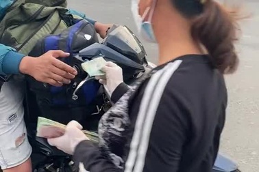 Người phụ nữ đi dép tổ ong đi phát tiền cho bà con rời TPHCM về quê