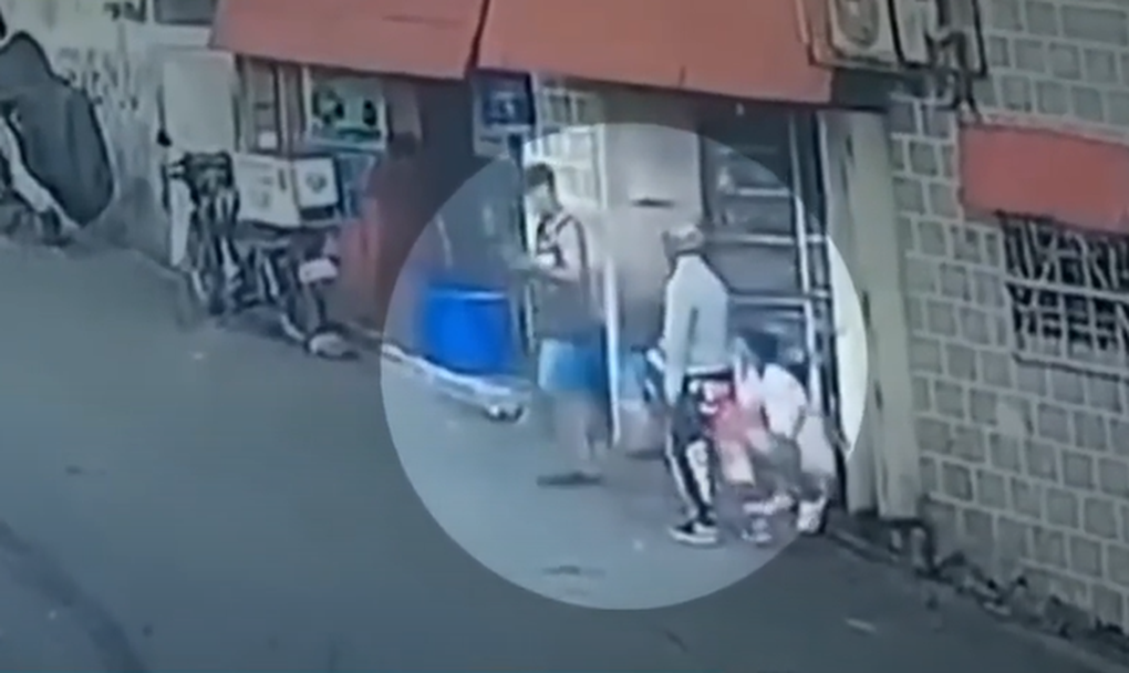 Khoảnh khắc Mark Russel Zapata (áo trắng) ngồi sử dụng smartphone trên đường và bị tên cướp (áo đen) giật mất (Ảnh: Cảnh sát thành phố Las Piñas).