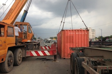 Xe vào cua gấp, thùng container lật nhào xuống đường