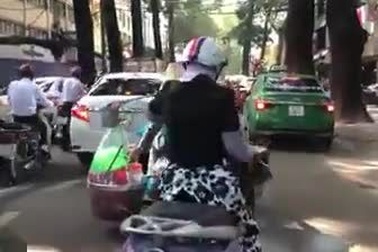 Người phụ nữ ngồi sau xe máy gánh theo lò than và nồi nước sôi cực kỳ nguy hiểm