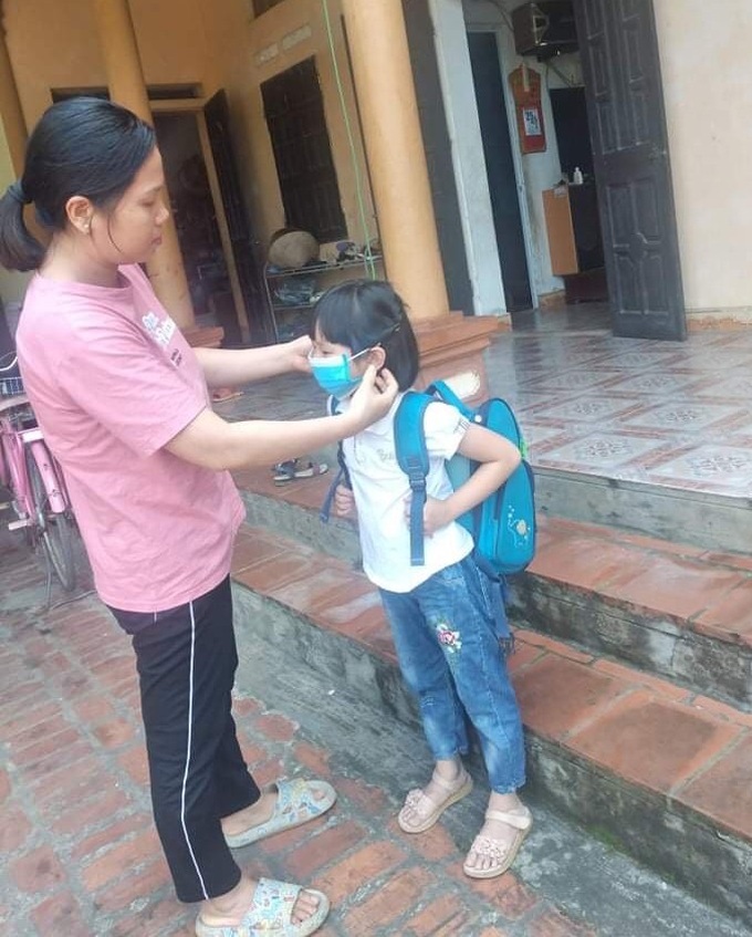 Cha mẹ hướng dẫn con cách đeo khẩu trang đúng, đảm bảo khẩu trang che kín miệng, cằm và mũi. Ảnh Lê Thúy