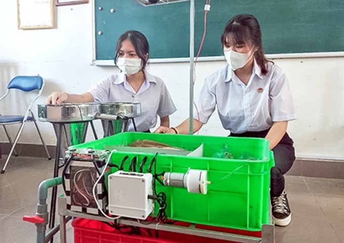 Hai em Diệu An (bên phải) và Ý Vi, bên sản phẩm máy ấp trứng cá thát lát ứng dụng công nghệ cảm biến.