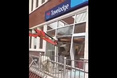 Thợ xây lái máy xúc phá hỏng cửa khách sạn.