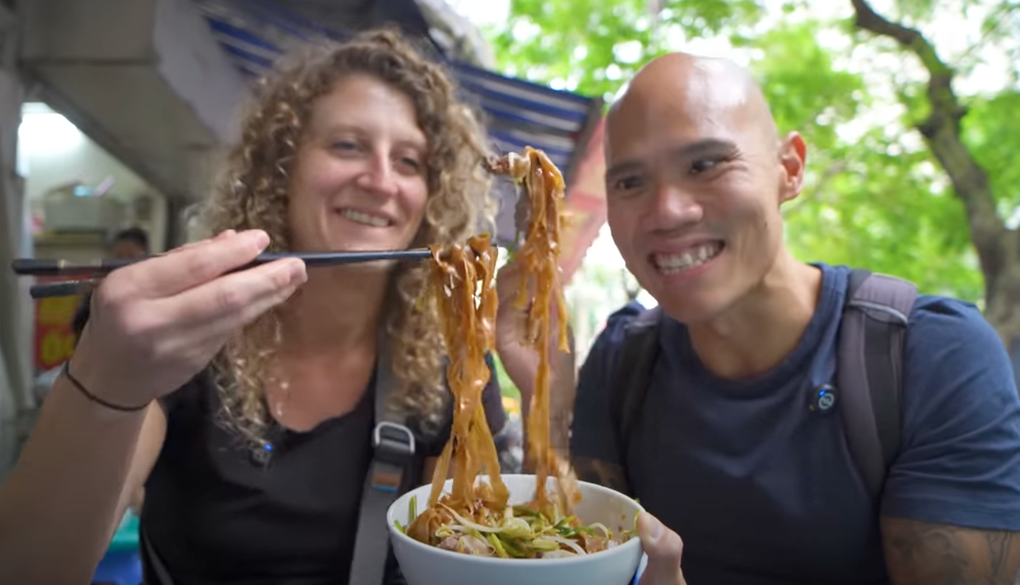 ភ្ញៀវទេសចរលោកខាងលិចចង់ដឹងអំពីចានគុយទាវដ៏ចម្លែកជាមួយសាច់ និងទំពាំងបាយជូរខ្មៅនៅទីក្រុងហាណូយ - ១ Khách Tây tò mò với bát mì lạ có thịt và nước dùng màu đen tại Hà Nội - 1