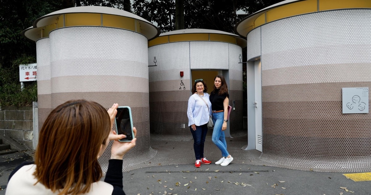 Du khách chụp ảnh trước một nhà vệ sinh công cộng trong dự án (Ảnh: Reuters).