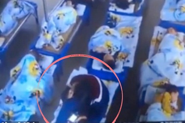 Giáo viên mầm non ngồi lên người học sinh, chơi điện thoại