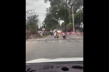 Người đi xe máy đua nhau vượt đường sắt dù chắn tàu đã hạ