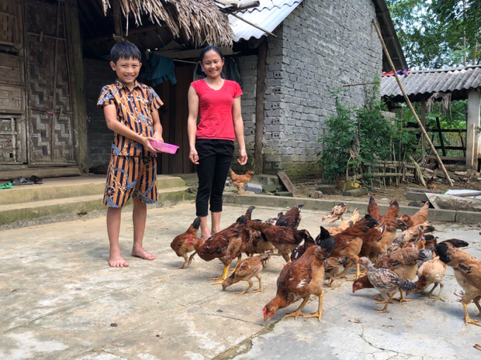 Thuận và mẹ em cùng đàn gà trong sân nhà mình. Ảnh: World Vision.