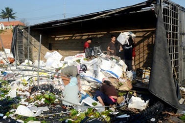 Người dân giúp tài xế xe tải thu gom hoa quả bị đổ ra đường