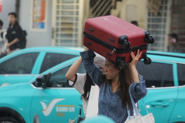 Người dân TPHCM đội vali đi chơi lễ dưới mưa lớn