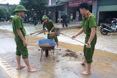 Công an đội mưa dọn bùn đất trên đường