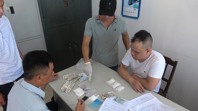 Đối tượng Mai Quốc Thành (áo phông trắng) và tang vật vụ án tại cơ quan Công an