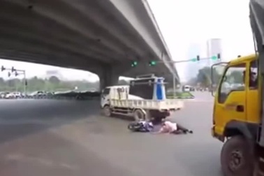 Luồn lách sai làn để vượt, người đi xe máy trượt ngã vào xe tải