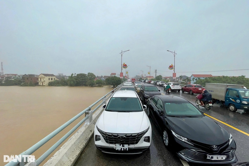 Mưa như trút, vỡ đập thủy lợi, người dân đưa ô tô lên cầu tránh lũ - 2