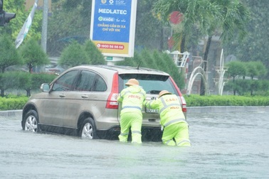 Cảnh sát dầm mưa giúp người dân đẩy xe qua đoạn đường ngập nước