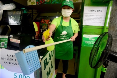 Nhân viên quán nước dùng gậy tự chế đưa tiền cho khách trong mùa dịch