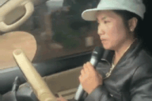 Người phụ nữ một tay lái ô tô, một tay cầm micro hát karaoke ngay trên xe