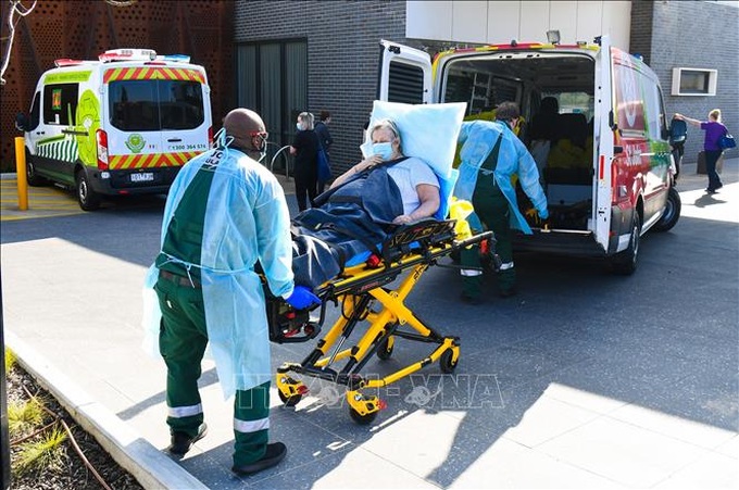 Nhân viên y tế chuyển bệnh nhân COVID-19 tới bệnh viện tại Melbourne, Australia. Ảnh: AFP/TTXVN
