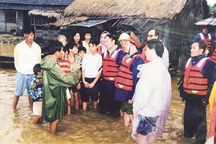 Vị Bộ trưởng đội mũ cối, quần xắn cao, mặc áo mưa đi trong bão lũ