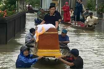 Nước lũ dâng cao, người dân dùng thuyền di chuyển quan tài người quá cố