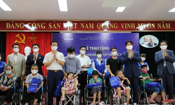 Phó Chủ tịch Thường trực UBND tỉnh Bắc Ninh Vương Quốc Tuấn và đại diện Samsung Việt Nam trao xe lăn cho người khuyết tật tại chương trình.
