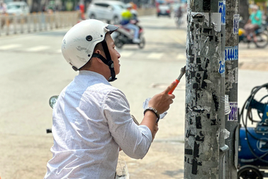 Dán quảng cáo lên cột điện TPHCM, người vi phạm bị bắt đi cạo bỏ