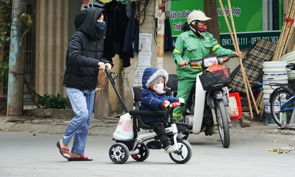 Trẻ em được bố mẹ bọc kín mít đi đường trong tiết trời lạnh giá ở Hà Nội - 1