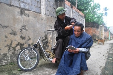 Người đàn ông cắt tóc trên xe lăn