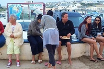 Cựu Thủ tướng Anh Cameron đi chân đất, ngồi ăn ở cạnh bãi đỗ xe