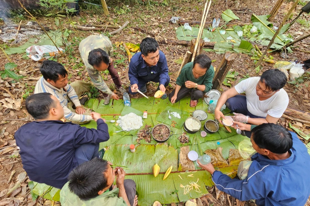 Bộ đội quy tập và người dân Lào dẫn đường trong bữa cơm giữa rừng khi tìm kiếm hài cốt quân tình nguyện Việt Nam (Ảnh: Trọng Kiên).