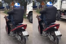 Nam thanh niên lái xe máy bằng chân, tay bấm điện thoại