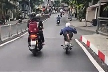 Nam thanh niên nằm trên yên xe máy chạy trên đường ở TPHCM