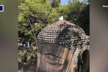 Du khách trốn bảo vệ, trèo lên đầu tượng Phật khổng lồ ngồi thiền