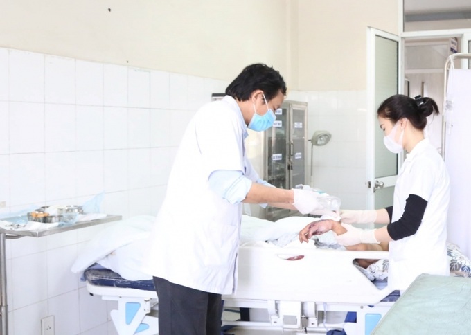 Các điều dưỡng Bệnh viện Đa khoa Phú Thọ thay băng cho bệnh nhi bị dập nát tay do tự chế pháo. Ảnh BVĐKPT