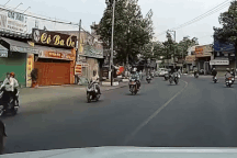 Người đàn ông đi xe máy đẩy bé trai đi xe đạp phóng băng băng trên đường